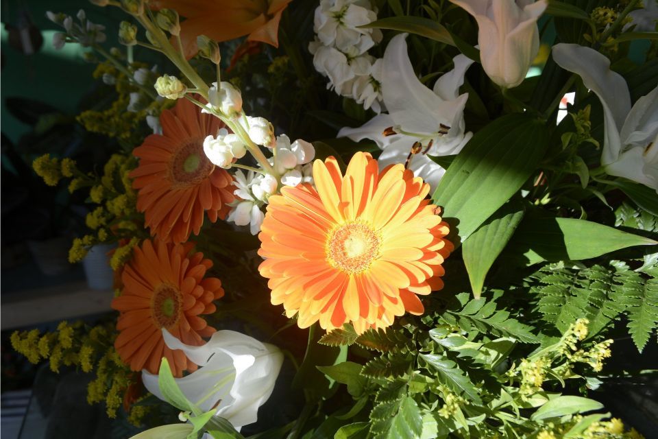 Gerbere arancioni in un bouquet con gigli bianchi e verde.