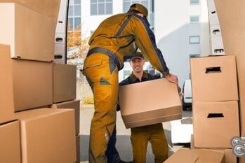 Movers Carrying Box Outside Truck On Street - packing supplies in CA