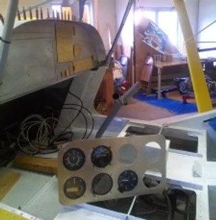 A plane is being built in a room with a lot of wires