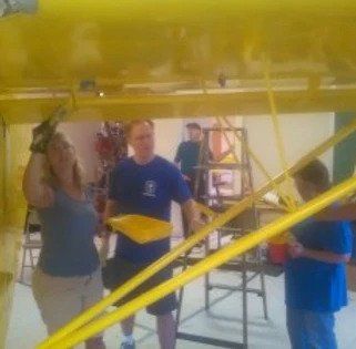 A group of people are working on a yellow object.