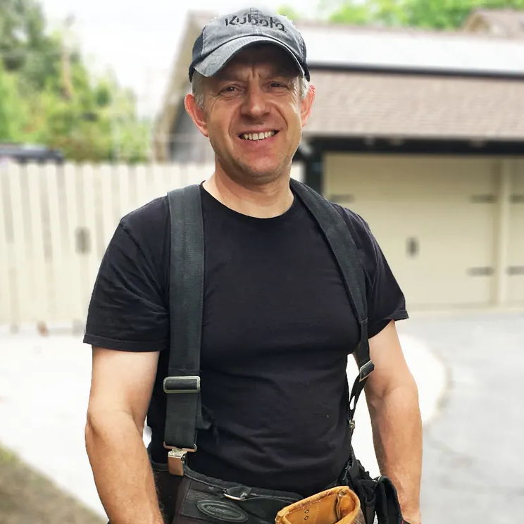 A man wearing a black shirt and a hat with the word kubota on it