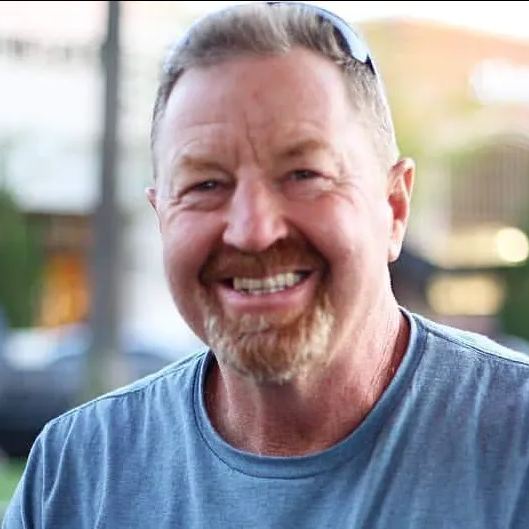A man with a beard and sunglasses is smiling for the camera.