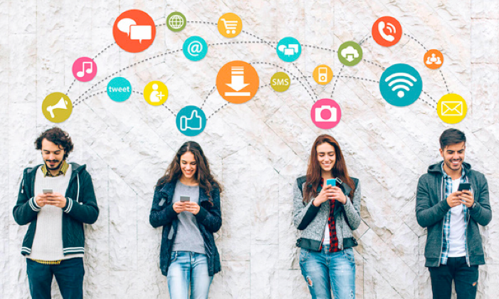 A group of people are standing next to each other looking at their phones.