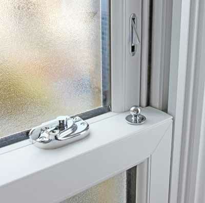 Close-up of a window latch and lock on a white frame beside frosted glass.