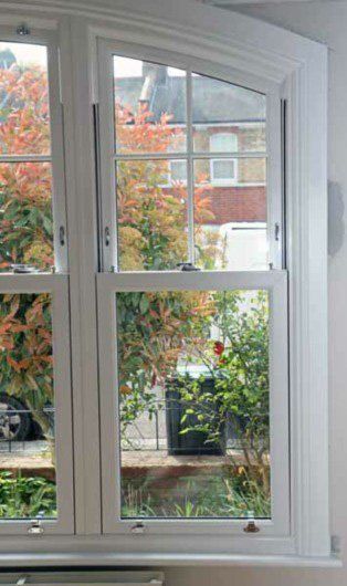 View through a white-framed window of autumn trees and a brick building outside