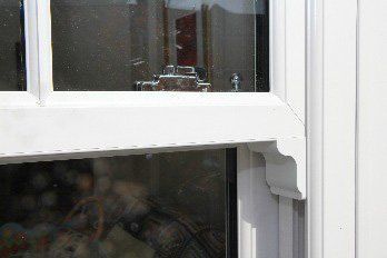 White-framed window with glass panes and a small decorative bracket detail on the right side