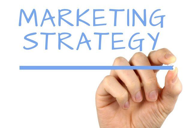Una mano sta scrivendo la parola strategia di marketing con un pennarello blu