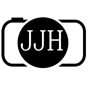 Black and white camera icon with a black circle in the middle containing the white letters