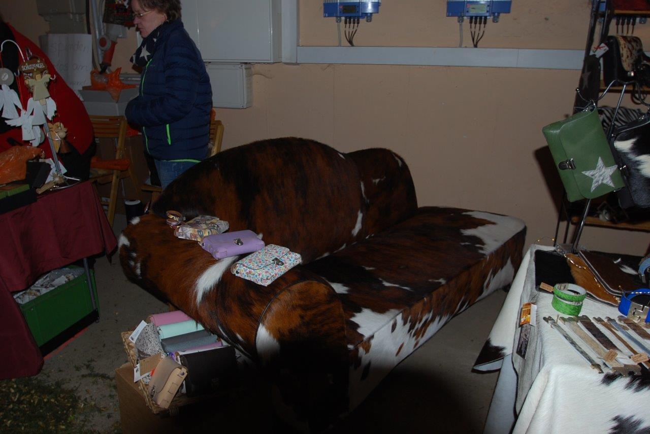 Eine Frau sitzt auf einem Stuhl neben einer Couch mit Kuhmuster