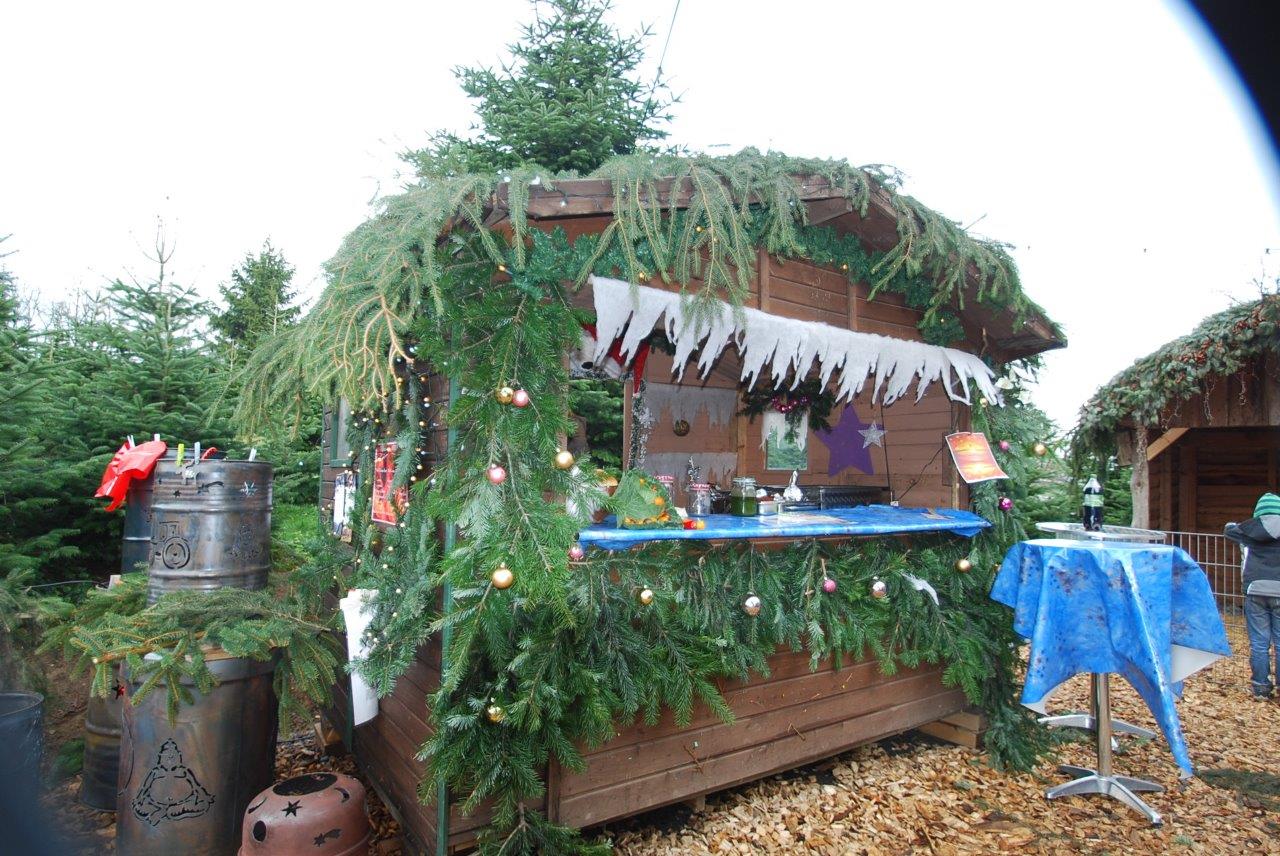 Ein Holzgebäude mit einem blauen Tisch davor ist weihnachtlich geschmückt.