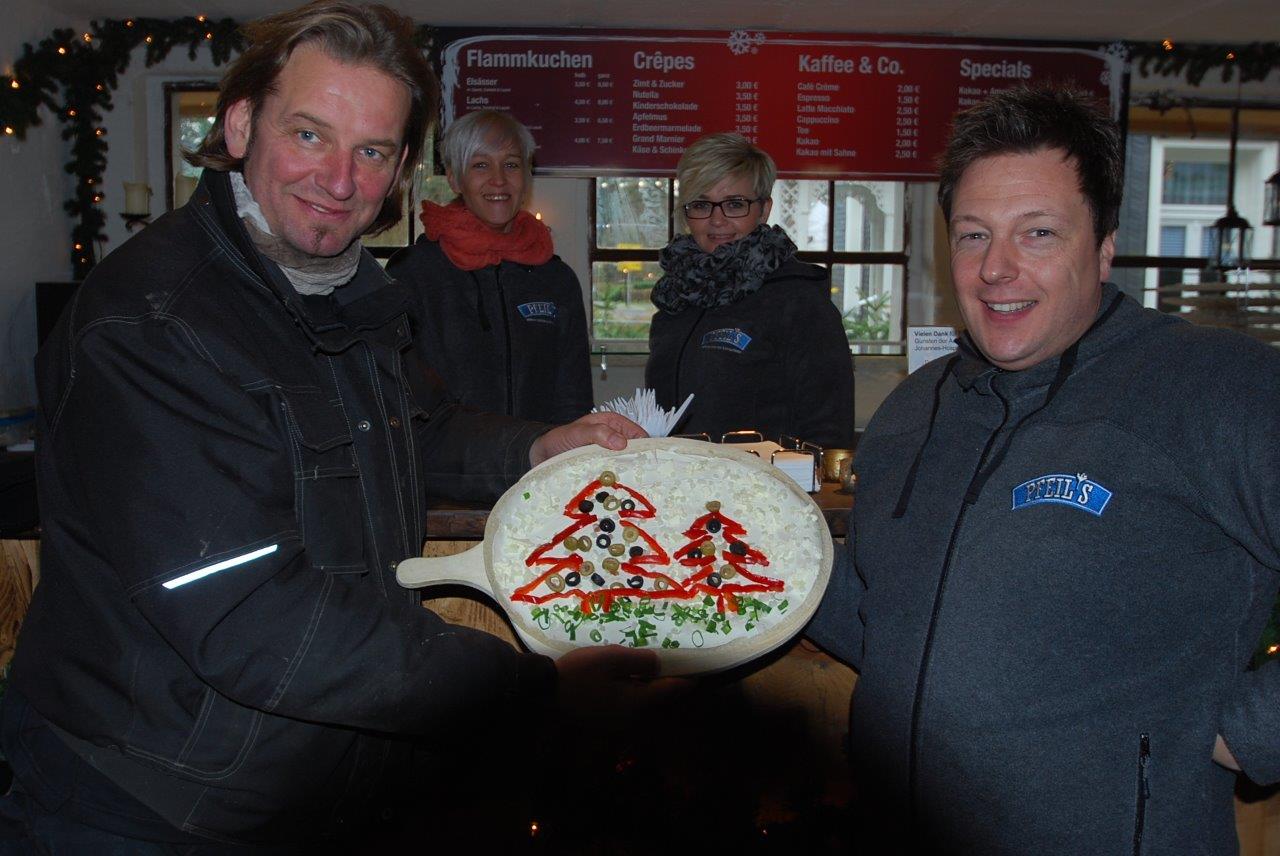Ein Mann hält eine Pizza mit einem Weihnachtsbaum darauf