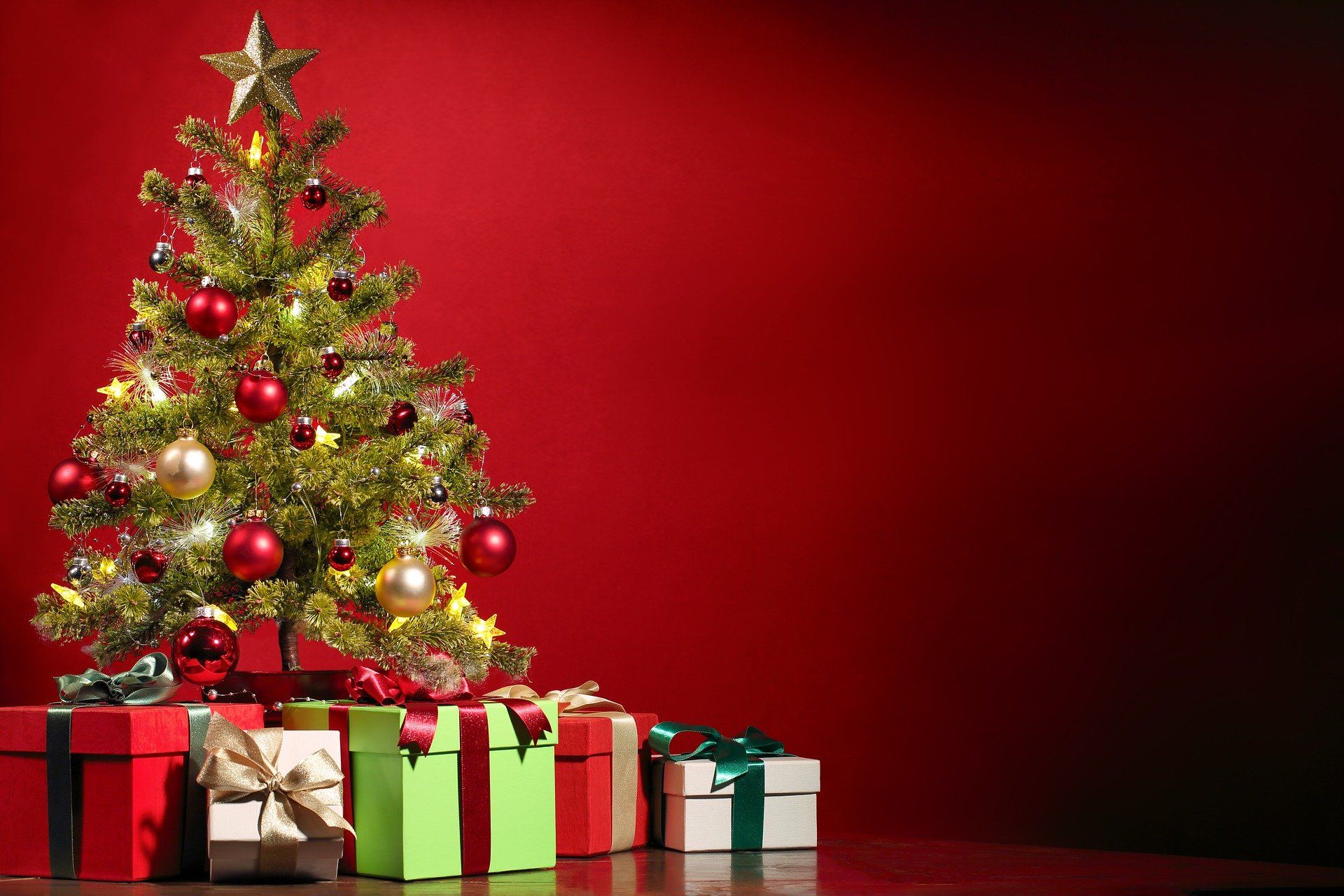 Ein Weihnachtsbaum mit Geschenken darunter auf rotem Hintergrund