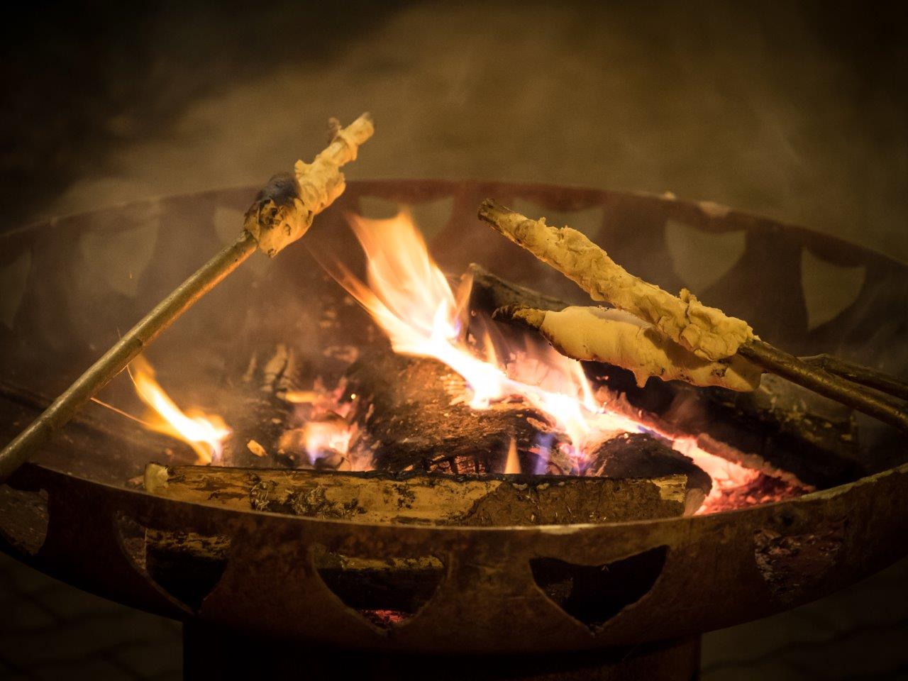 Stockbrot an einem Ast über einem Lagerfeuer