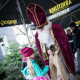 Weihnachtsmann gibt Kindern auf Weihnachtsmarkt Geschenke
