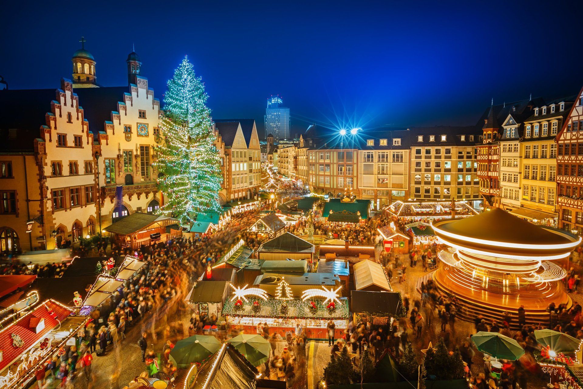 Vogelperspektive auf stark beleuchteten Weihnachtsmarkt auf einem Markplatz voll mit Menschen