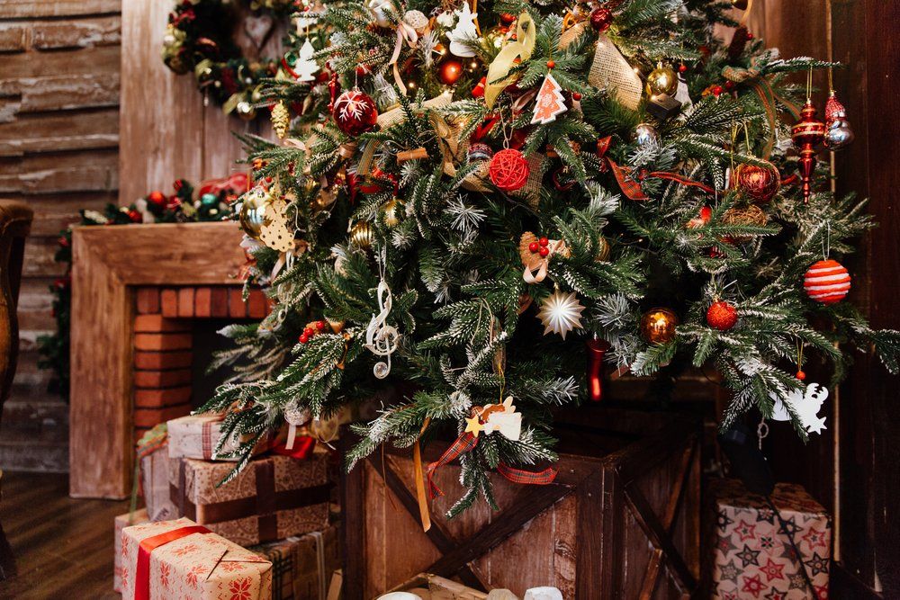 Ein Weihnachtsbaum mit Geschenken darunter in einem Wohnzimmer.