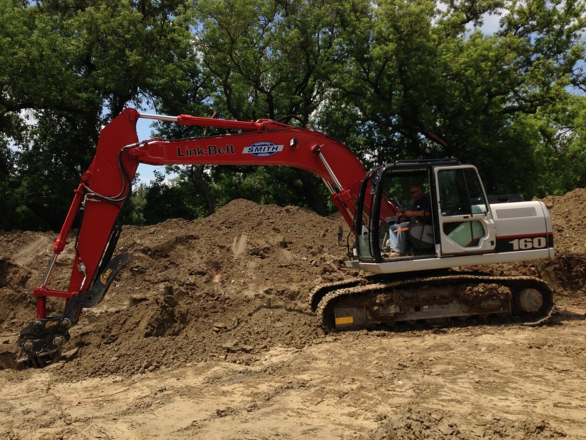 Red and white excavator digging dirt on a construction site.