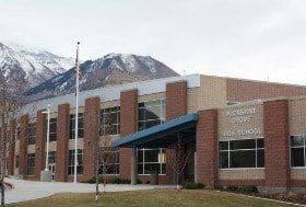 A large brick school building with mountains in the background.