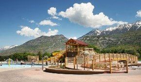 A water park with a slide and mountains in the background.