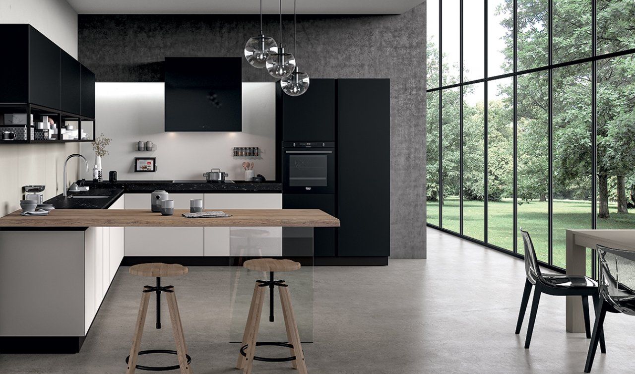 Una cucina con mobili neri, un tavolo di legno, sgabelli e una grande finestra.