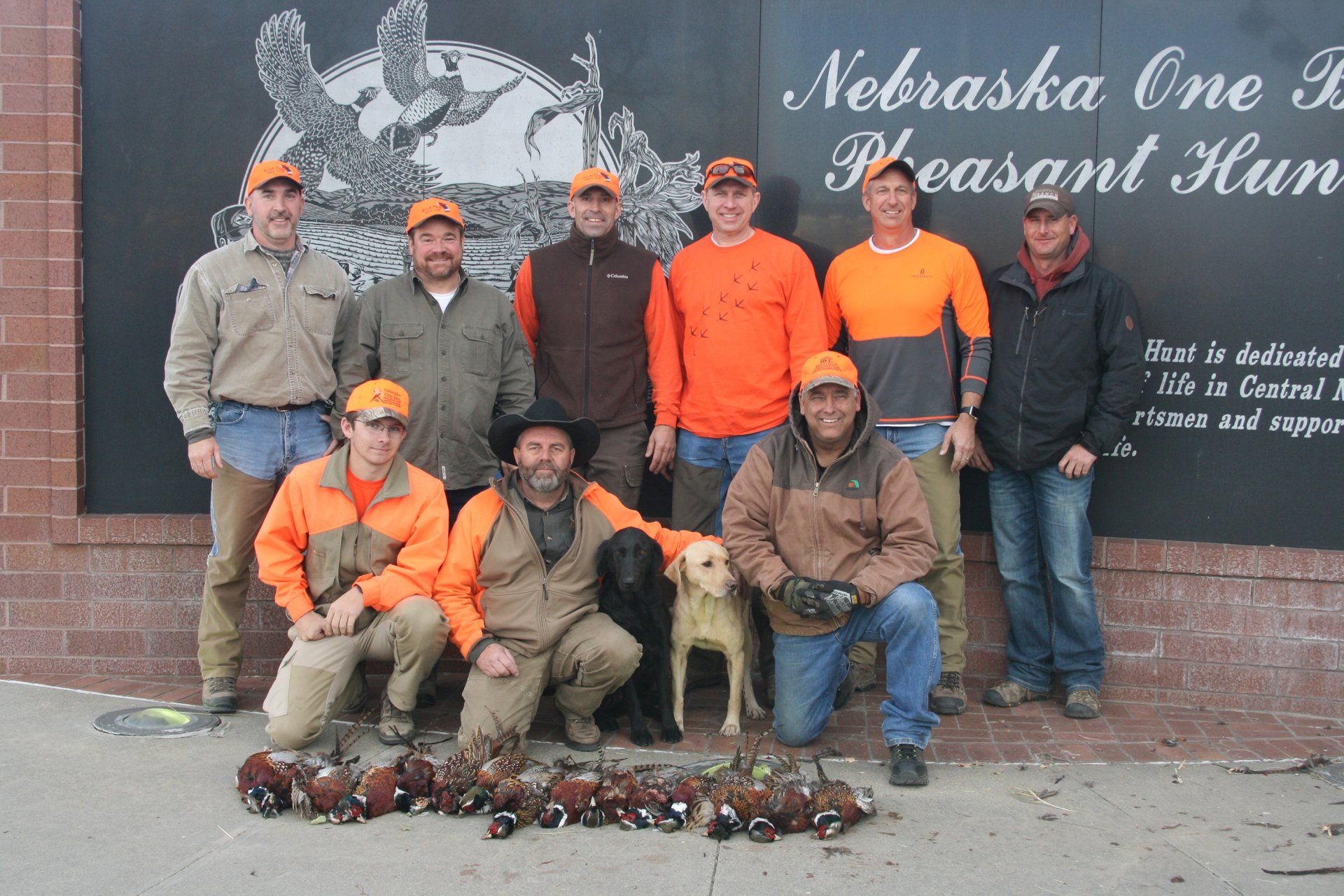 Group of hunters with pheasant, wearing orange in Nebraska.