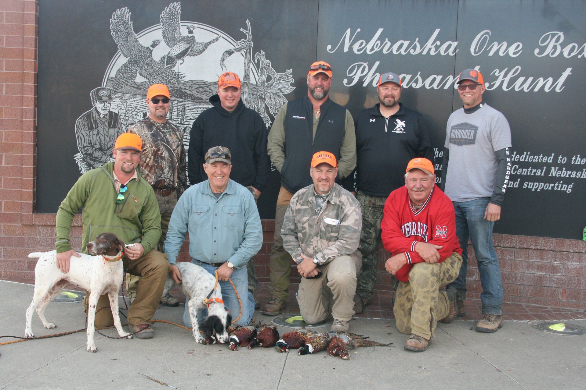 Group of pheasant hunters in Nebraska pose with dogs and birds.