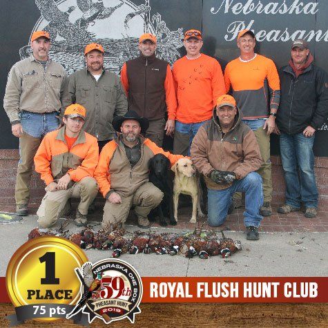 Group of hunters with dogs, trophies, and pheasant haul in Nebraska.