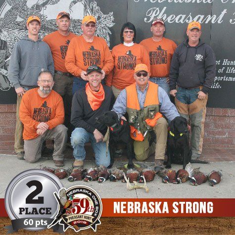 Group of people with dogs posing with harvested pheasants; 