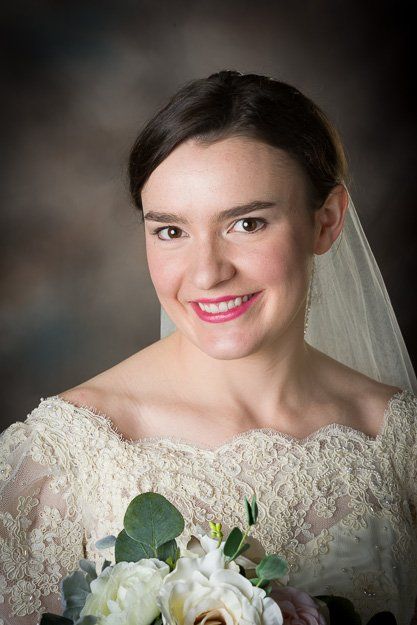 a woman in a wedding dress and veil is holding a bouquet of flowers .