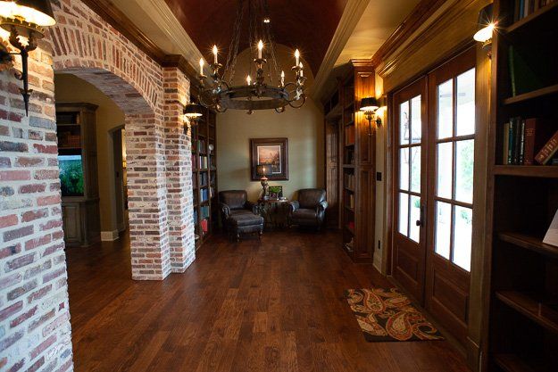 a hallway with hardwood floors , brick walls and a chandelier .