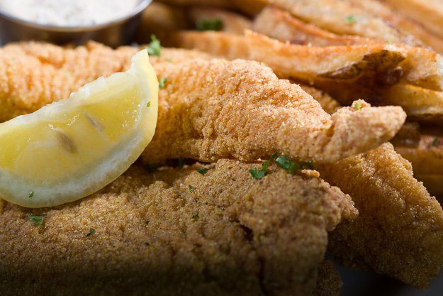 a close up of fried fish and french fries with a slice of lemon .