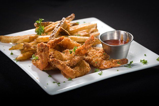 a plate of fried shrimp and french fries with a side of ketchup .