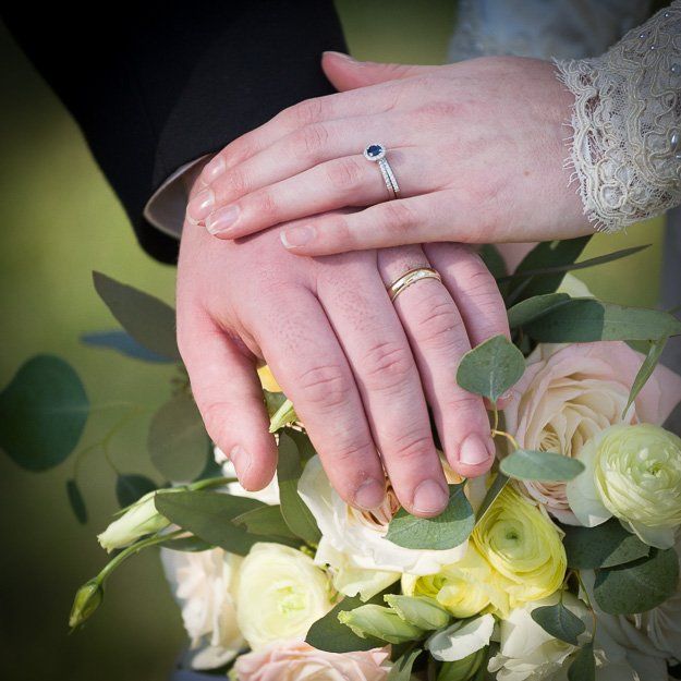 a bride and groom holding hands with their wedding rings on