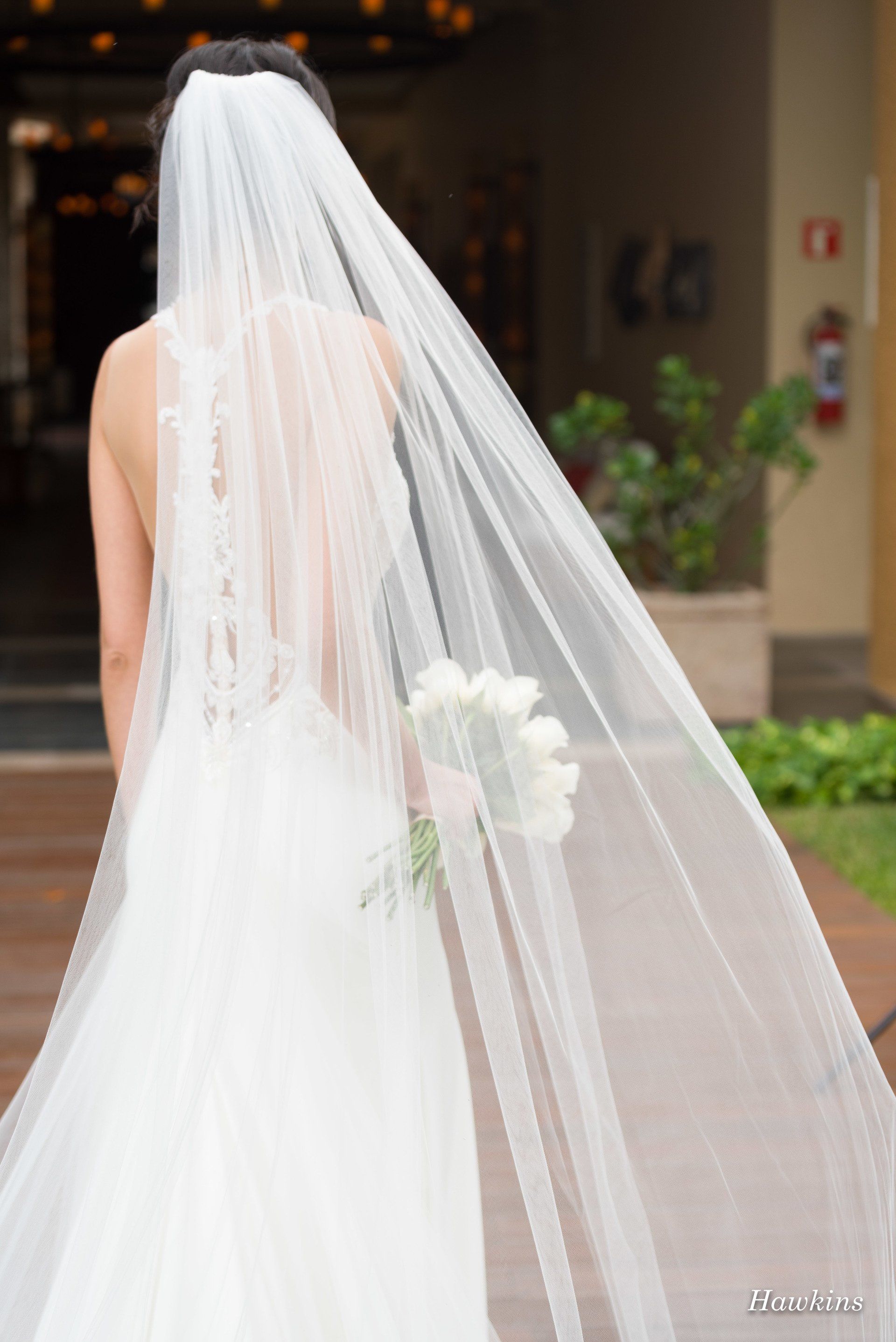 a bride wearing a long white veil holds a bouquet of white flowers
