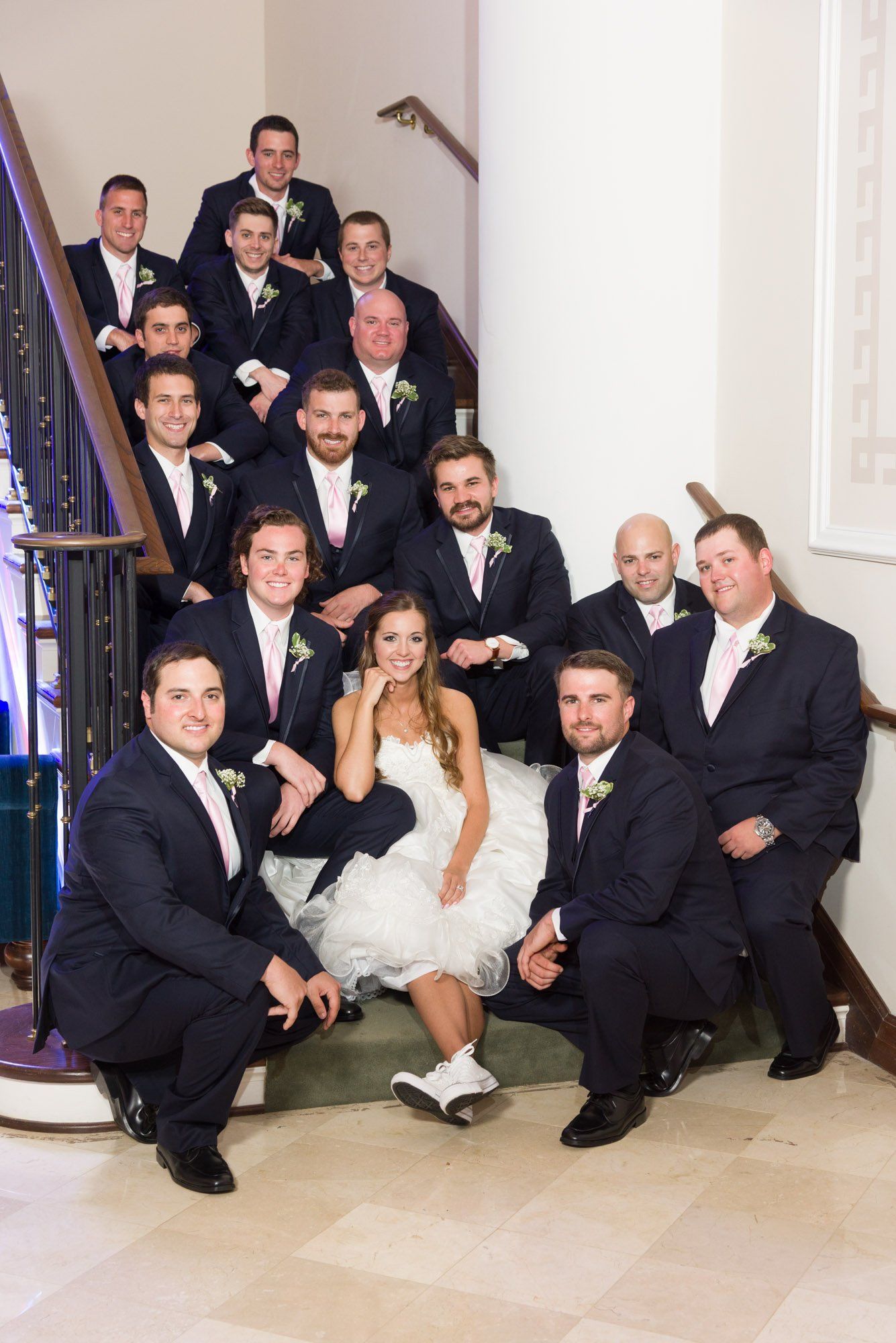 the bride and groom pose with their wedding party on the stairs