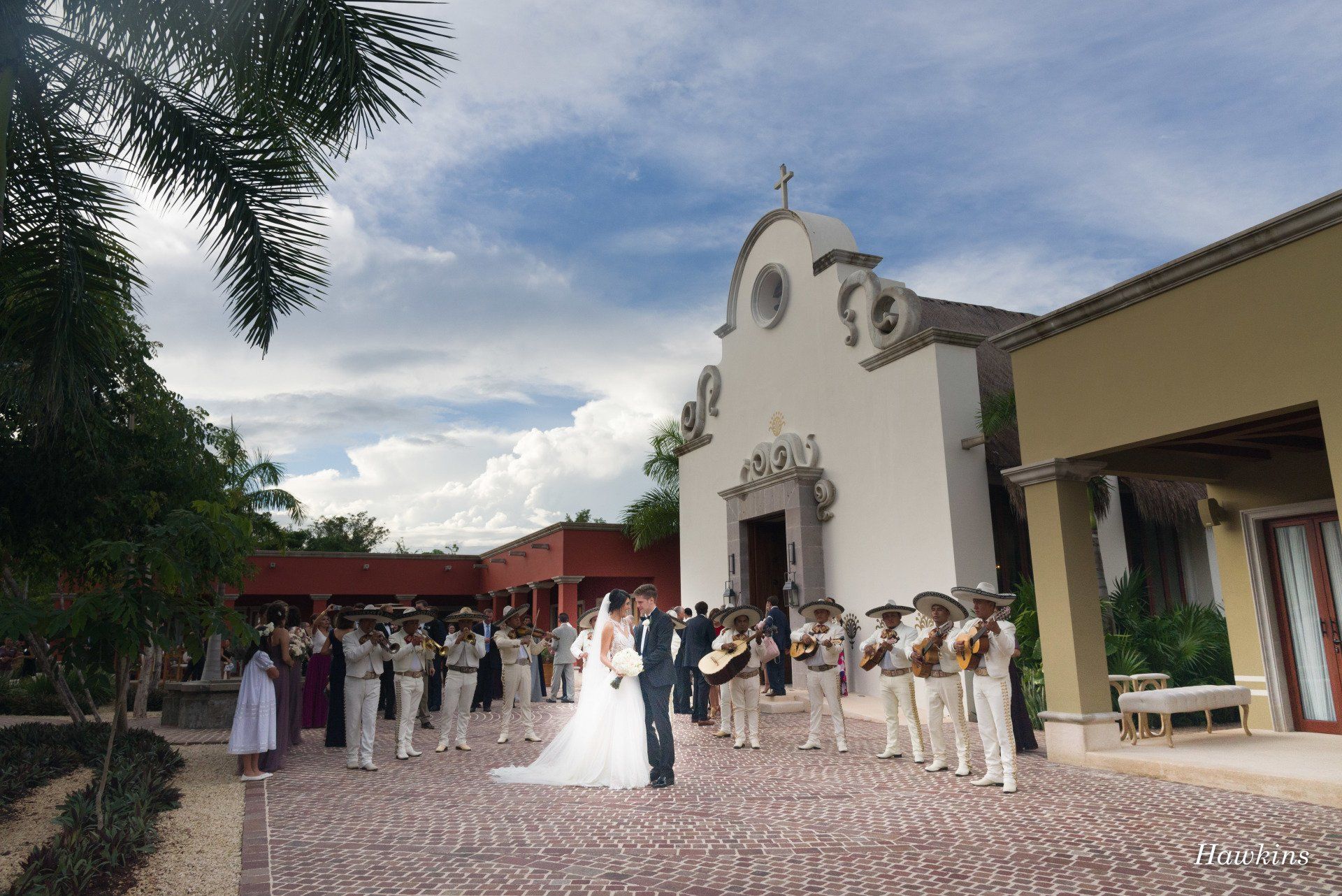a bride and groom are standing in front of a church with mariachi players