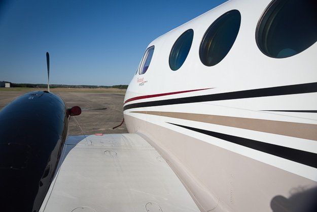 a small airplane is parked next to a large airplane on a runway .