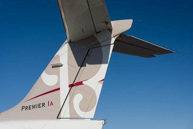 the tail of a premier ia airplane is shown against a blue sky .
