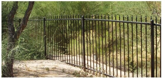 Black metal fence in front of a green natural background.