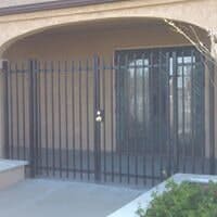 Black metal security gate and door, protecting a doorway.