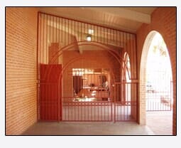 Red metal security gates in a brick archway, leading into a building.