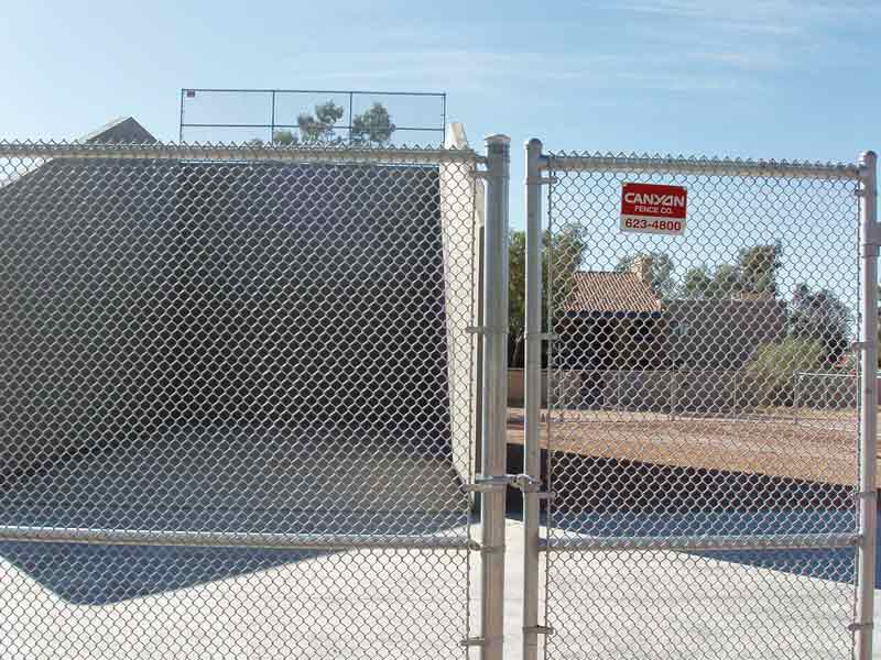 Chain-link fence with gate, enclosing a sports field. A 