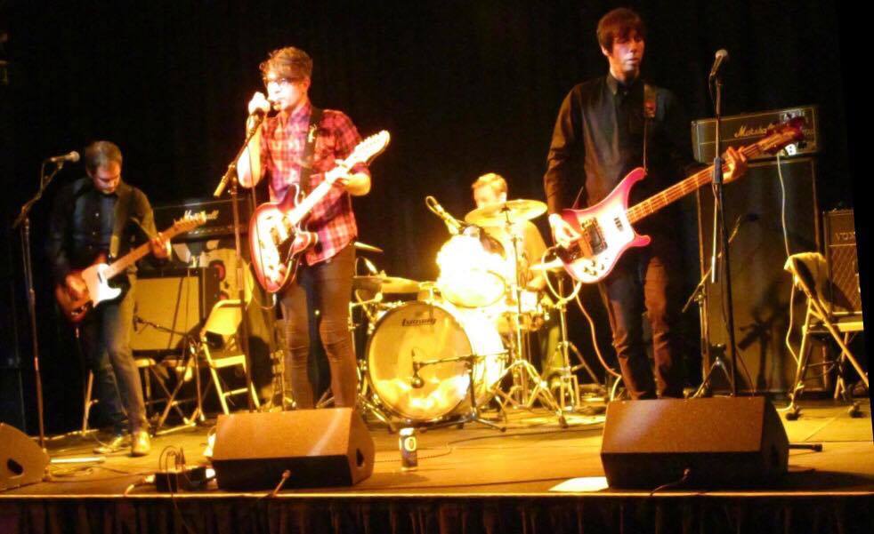 A group of men playing guitars on a stage
