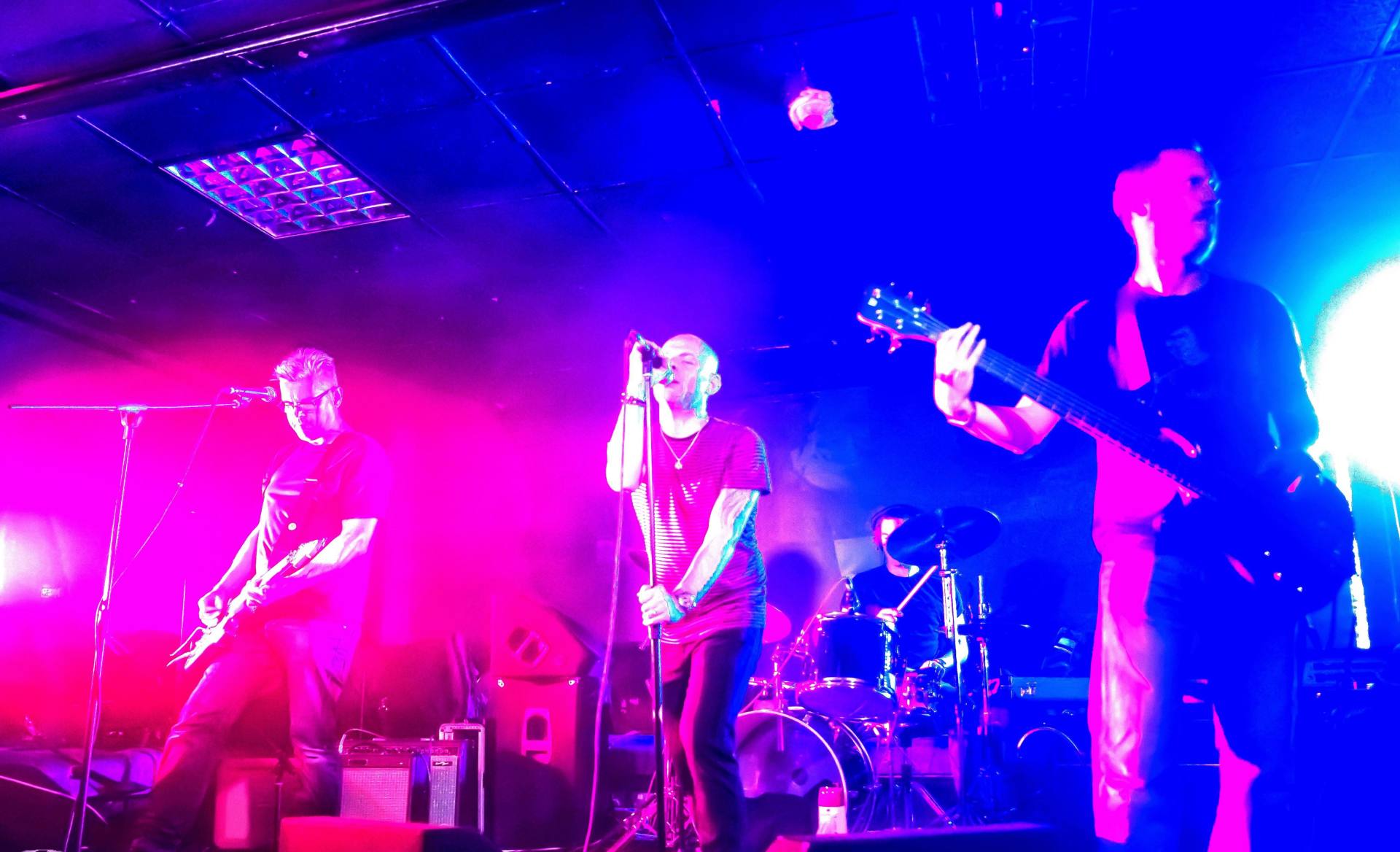 A group of people are playing instruments on a stage in a dark room.