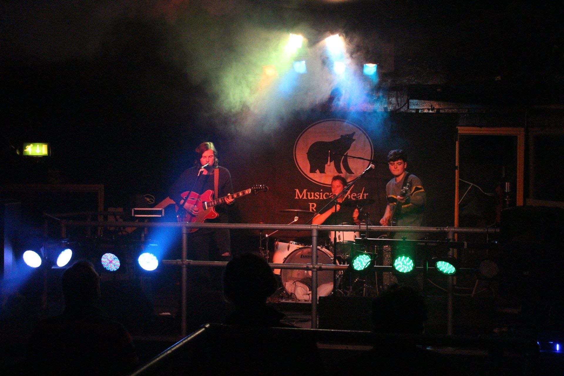A group of people playing instruments on a stage in front of a sign that says marcel