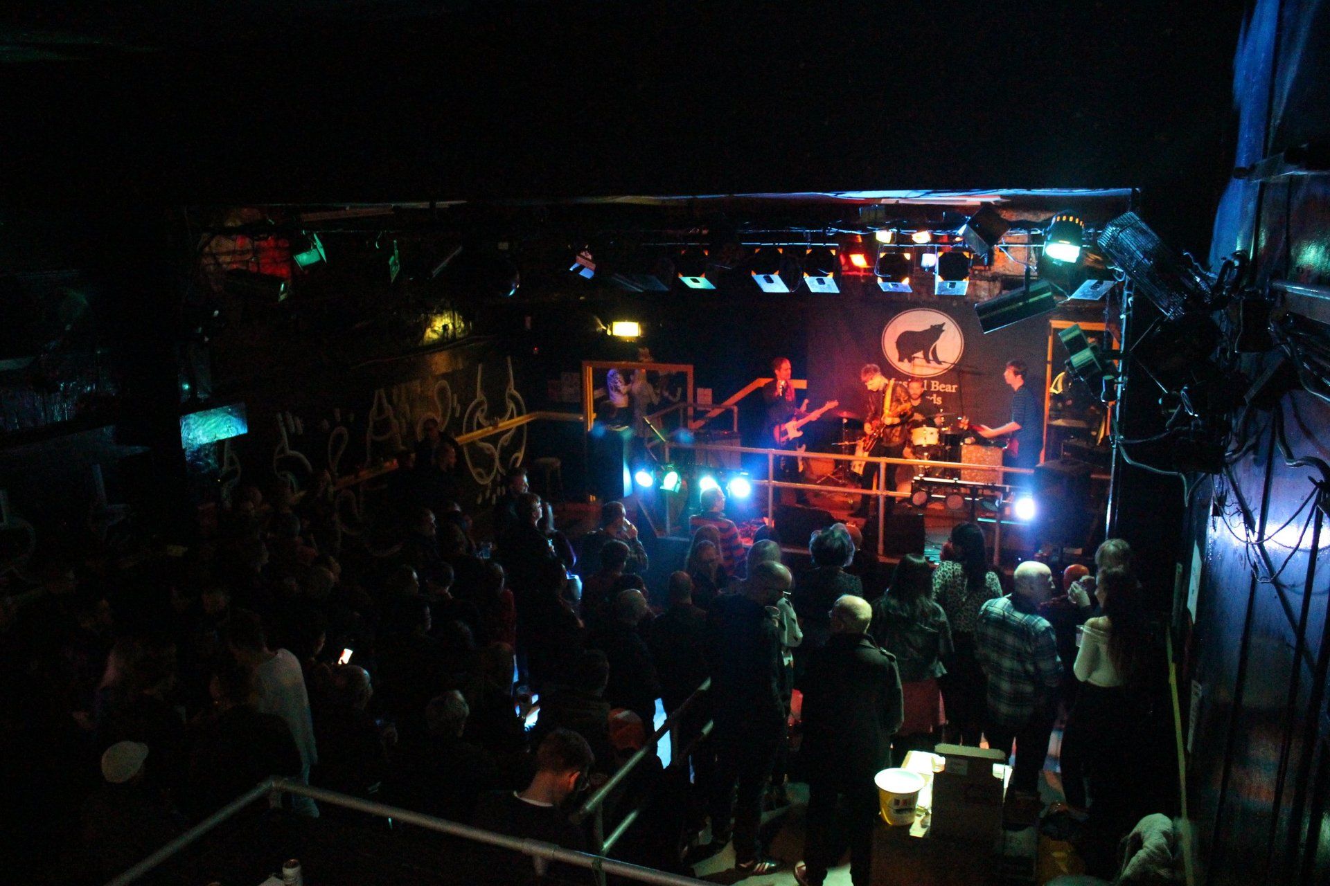 A crowd of people are gathered in a dark room at a concert