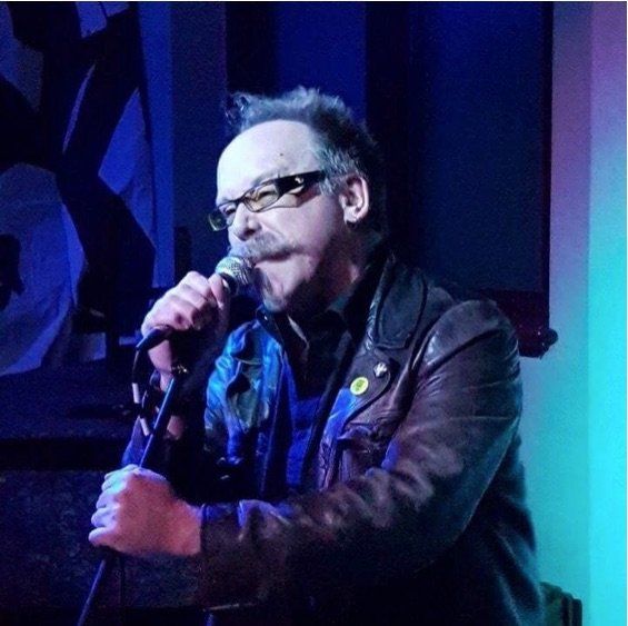 A man wearing glasses is singing into a microphone