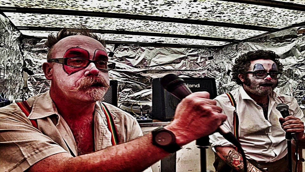 A man with red paint on his face is holding a microphone.