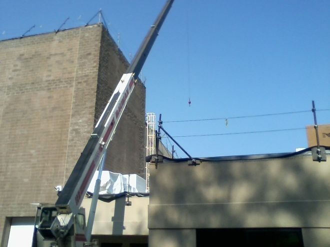 A crane lifting something over a building on a sunny day.