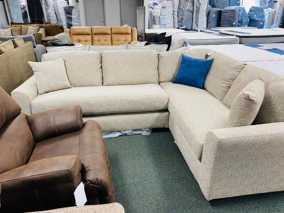 Beige sectional sofa with blue pillow in a furniture store.